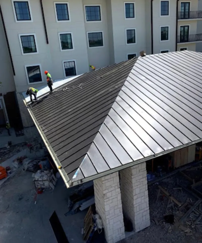 Crew installing standing seam metal roof panels on a commercial project in Plattsburgh